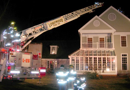 LFC crews preparing to ventilate the roof at a working house fire.